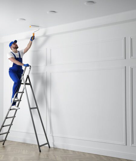 commercial painting contractor painting ceiling with white dye indoors