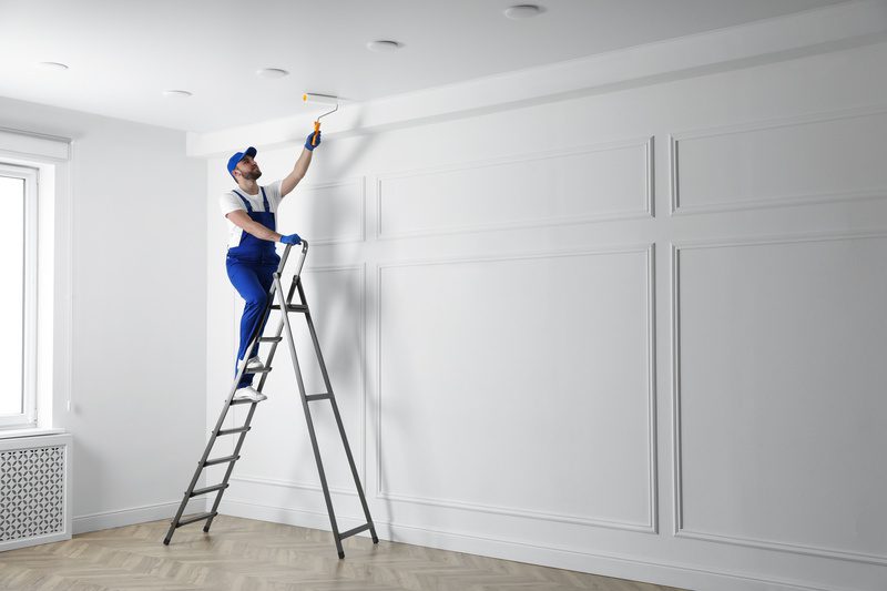 commercial painting contractor painting ceiling with white dye indoors