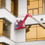Commercial painting workers working at height in lifting paint bucket.