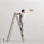 Rear view of a painter painting a wall on a ladder