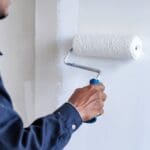 Commercial painting contractor painting a wall with white paint