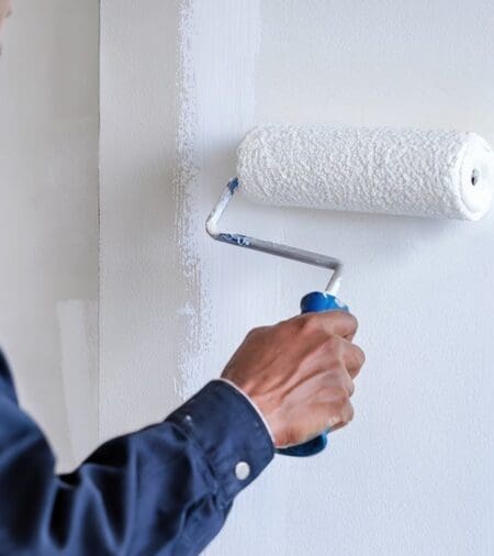 Commercial painting contractor painting a wall with white paint